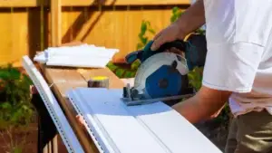 Professional handyman using circular saw to cut exterior siding material for precise installation - Concord's Handyman Crew siding services in Concord NC
